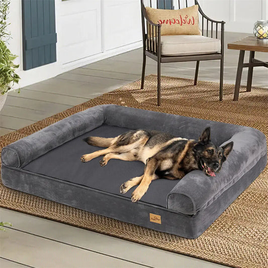 Dog lying on a large gray pet bed outdoors on a wooden deck.